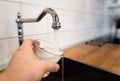 Potable water and safe to drink. man filling a glass of water from a stainless steel kitchen tap. male`s hand pouring water into Royalty Free Stock Photo