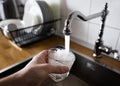Male`s hand pouring water into the glass from chrome faucet to drink running water with air bubbles. potable water and safe to