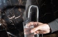 Man filling glass with water from tap in kitchen Royalty Free Stock Photo