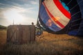 Man filling a hot air balloon on the ground in the field sky and a shining sun background