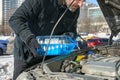 Man filling a windshield washer tank of a car by antifreeze on busy Moscow street in winter Royalty Free Stock Photo