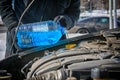 Man filling a windshield washer tank of a car by antifreeze Royalty Free Stock Photo