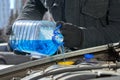 Man filling a windshield washer tank of a car by antifreeze in winter outdoors Royalty Free Stock Photo