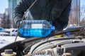 Man filling a windshield washer tank of a car by antifreeze on winter Moscow street Royalty Free Stock Photo