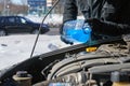 Man filling a windshield washer tank of a car by antifreeze on winter Moscow street Royalty Free Stock Photo