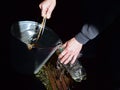 A man fills a plastic bottle with spring water from a bucket near an old well