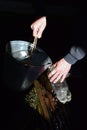 A man fills a plastic bottle with spring water from a bucket near an old well