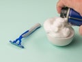 A man fills a white bowl with shaving foam