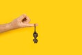 Man finger holding ornate iron keys on a yellow background