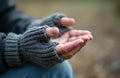 Man in fingerless gloves extends open hands, asking for help or alms. Focus on gesture conveys need, poverty, or plea. Soft Royalty Free Stock Photo