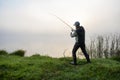 Man fisher fishing on foggy sunrise.