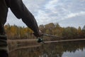 Man fisherman catches a fish on a fishing rod with a reel on the lake against the background of the forest and sky with clouds Royalty Free Stock Photo