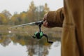 Man fisherman catches a fish on a fishing rod with a reel on the lake against the background of the forest and sky with clouds Royalty Free Stock Photo