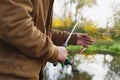 Man fisherman catches a fish on a fishing rod with a reel on the lake against the background of the forest and sky with clouds Royalty Free Stock Photo