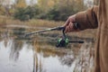 Man fisherman catches a fish on a fishing rod with a reel on the lake against the background of the forest and sky with clouds Royalty Free Stock Photo