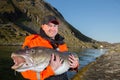 Man fisherman holding a fish ogromnyu Cod. Smiling Royalty Free Stock Photo