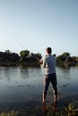 A man fisherman on the river bank catches a fish Royalty Free Stock Photo