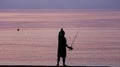 Man Fishing Alone in the Sea at Sunrise or Sunset