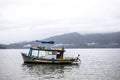 Man fishing on a fishing boat in Paraty, Brazil with hills on the background