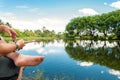 Man fishing, holding a rod on a lake with a beautiful nature around.