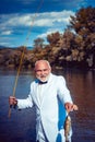 Man fishing on the lake. With fish. Summer vacation. Retired mature bearded male human in suit. Brutal man stand in Royalty Free Stock Photo