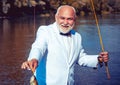 Man fishing on the lake. With fish. Summer vacation. Retired mature bearded male human in suit. Brutal man stand in Royalty Free Stock Photo