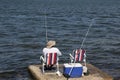 Man fishing on a lake or river or sea. fisherman sits on a chair with two fishing rods. man sits with his back.
