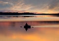 Man fishing on lake from small rowing boat at sunset or sunrise time. Fisherman silhouette at sunset Royalty Free Stock Photo