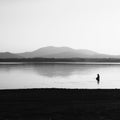 A man is fishing in the lake at sunset. Wetland and mountain landscape Royalty Free Stock Photo