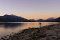 Man fishing on Lake Wakatipu at sunset with the amazing view of mountains behind. Otago, New Zealand Royalty Free Stock Photo