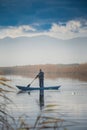 Man fishing in the misty river, capturing fish with a net from the boat in Metkovic, Croatia Royalty Free Stock Photo