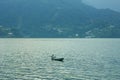 Man is fishing with nets in a lake against a background of green mountains. fisherman in a wooden boat with a paddle Royalty Free Stock Photo