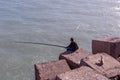 Man Fishing From Rocks On the edge of the sea bank, a cat watches attentively to steal fish, Take in cadiz, Andalusia, Spain