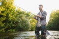 Man with fishing rod, fisherman men in river water outdoor. Catching trout fish in net. Summer fishing hobby Royalty Free Stock Photo