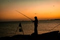 Man fishing with fishing rod in sunset, silhouette.