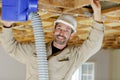 Man fitting cables into junction box in roofspace Royalty Free Stock Photo