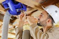 Man fitting cables into junction box in roofspace Royalty Free Stock Photo