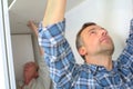 man fitting plasterboard ceiling