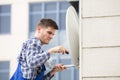 Man Fitting TV Satellite Dish On Wall Royalty Free Stock Photo