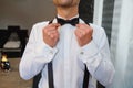 Man fixing his bow tie. Man groom in wedding suit with a bow tie. Close-up Royalty Free Stock Photo