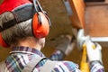 Man fixing metal frame using angle grinder on attic ceiling covered with rock wool