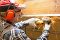 Man fixing metal frame using angle grinder on attic ceiling covered with rock wool