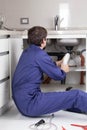 Man fixing a pipe sitting on the floor Royalty Free Stock Photo