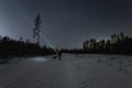 A man with a flashlight in the forest on the road, a ghost of a wolf stands nearby, the starry sky in winter Royalty Free Stock Photo