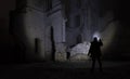 A man with a flashlight near the ruins of an old castle