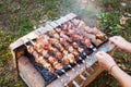 A man flips pork skewers grilled over coals on a brick grill. Delicious weekend barbecue Royalty Free Stock Photo