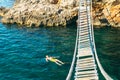 man floating in sea water on back. bay with rocky beach and suspension bridge Royalty Free Stock Photo