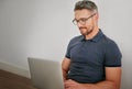 Man, floor and wall on laptop with sitting for relax in casual for social media with technology for internet. Male Royalty Free Stock Photo