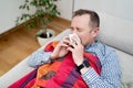 Sick man blowing his nose lying on the sofa. Royalty Free Stock Photo