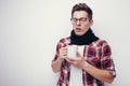 Man with flu and fever wrapped holding cup of healing tea isolated over white.